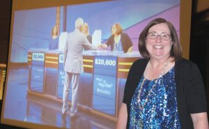 During a watch night party at Columbia Country Club, Dr. Cheryl Guy, Principal of Westwood High School, stands next to a big screen showing Jeopardy host Alex Trebek congratulating her on her big win on the show Friday night. (Photo/Barbara Ball)